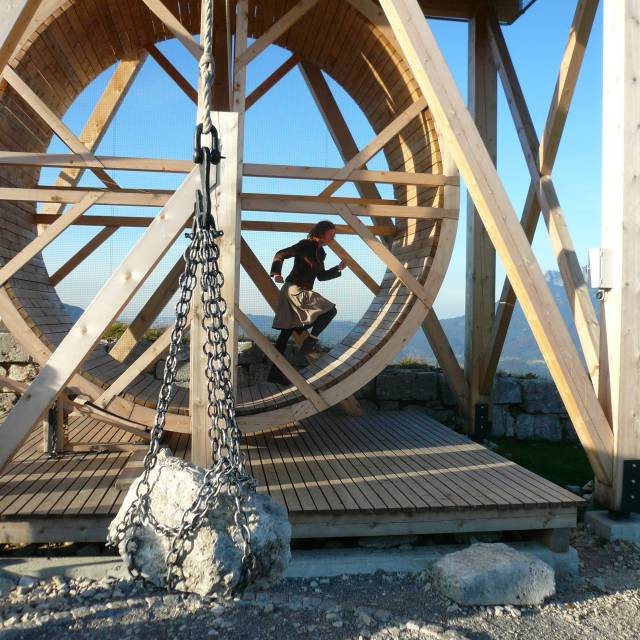 Historic wooden wheel with person in medieval clothing inside treadmill construction